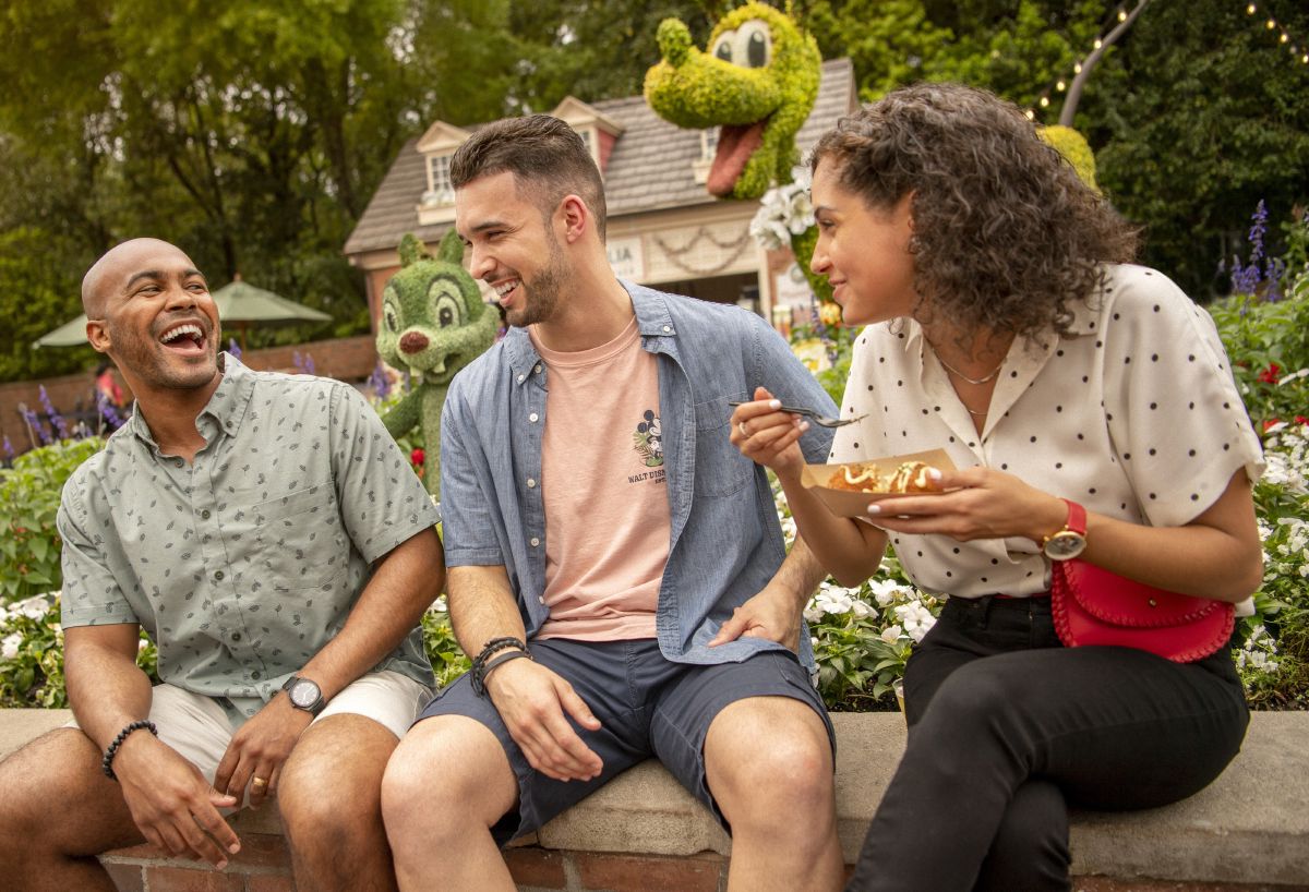 Young adults walk through EPCOT's World Showcase near a flower topiary, Walt Disney World Resort.