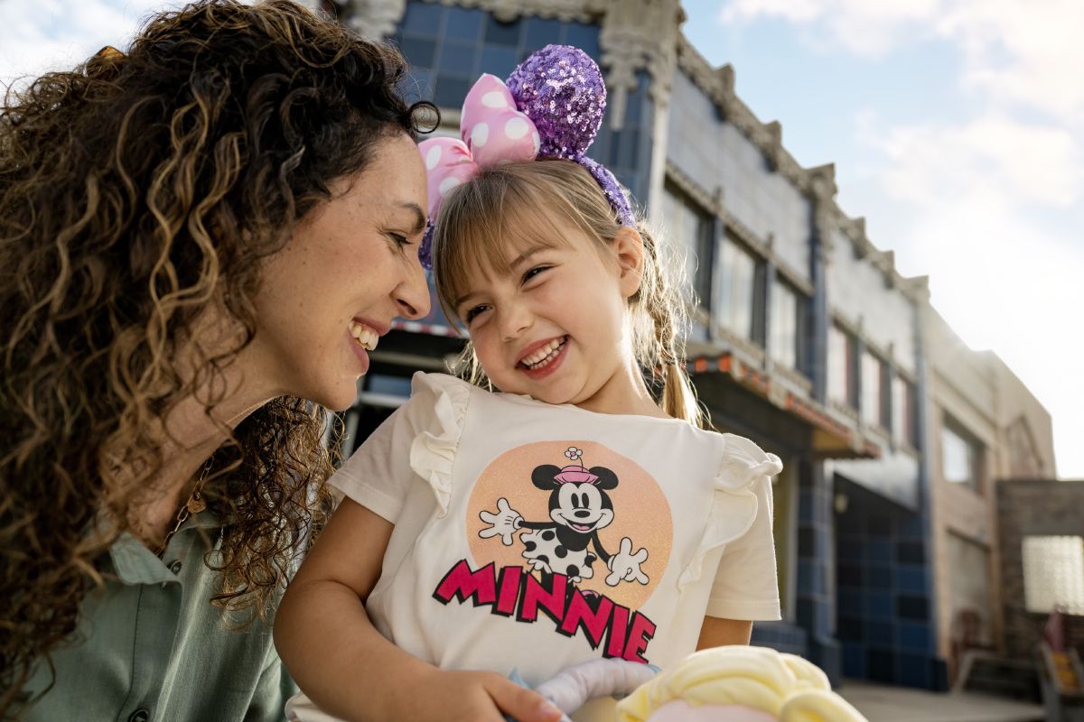 A young family smiles together at Disney's Hollywood Studios, Walt Disney World Resort.