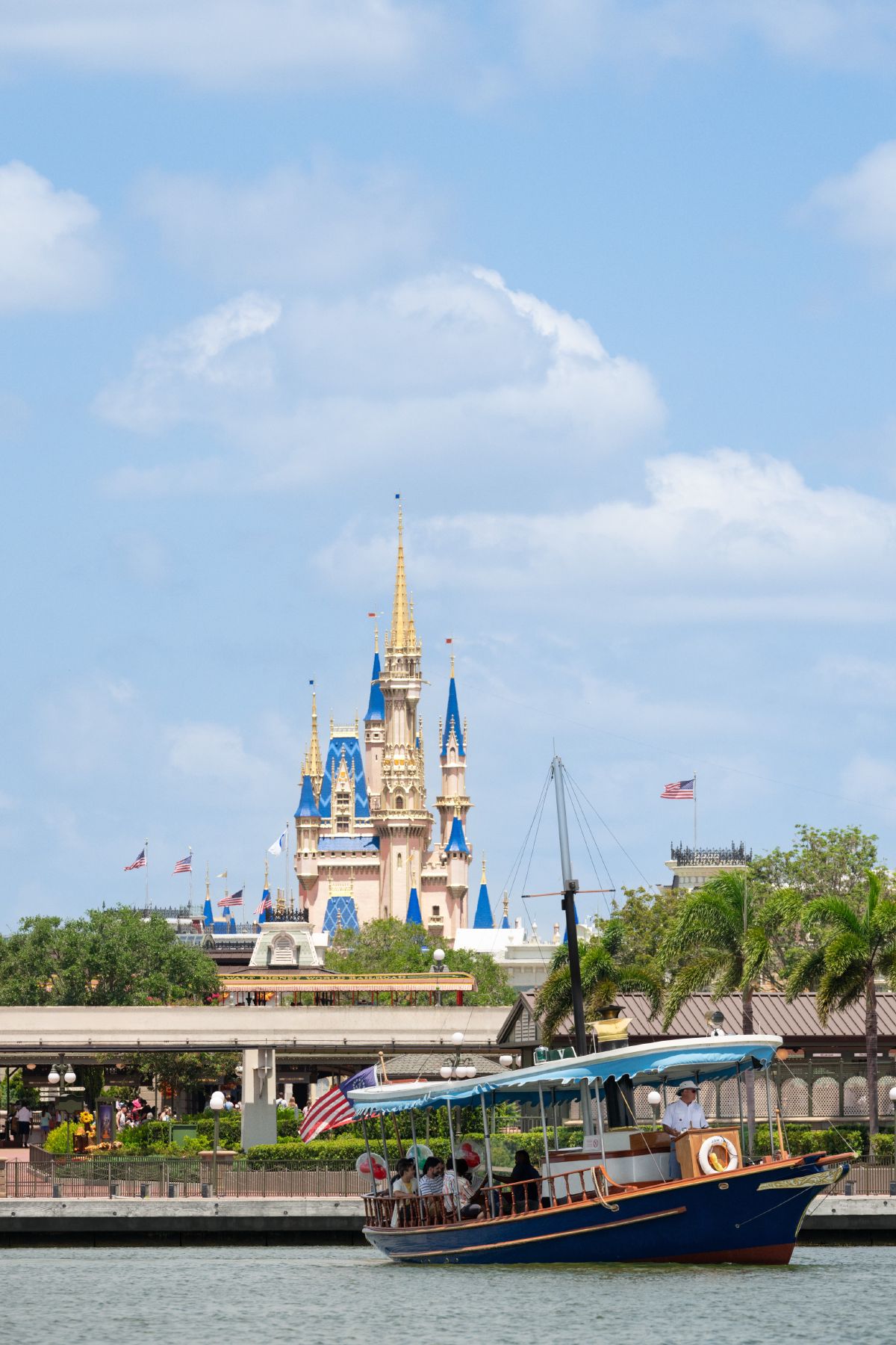 A water taxi carrying guests across Seven Seas Lagoon with Cinderella Castle rising behind it at Magic Kingdom Park.