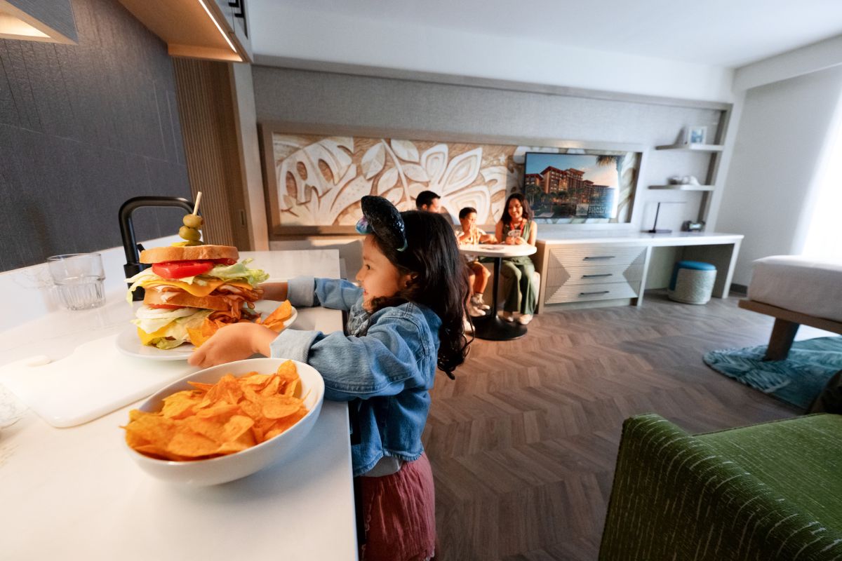 The kitchen and living space inside a studio villa at Disney's Polynesian Village Resort at Walt Disney World Resort, with a full-size refrigerator, sink, and dining area.