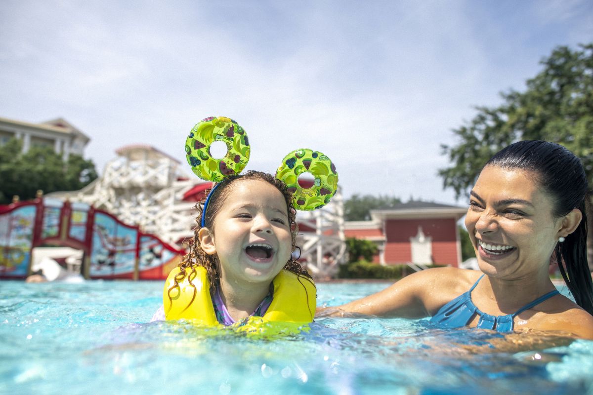 A mother and daughter laughing together in the pool at Disney's BoardWalk Inn, the child wearing mouse ears and floaties — a perfect example of why rest days at the resort pool make a Walt Disney World trip better.