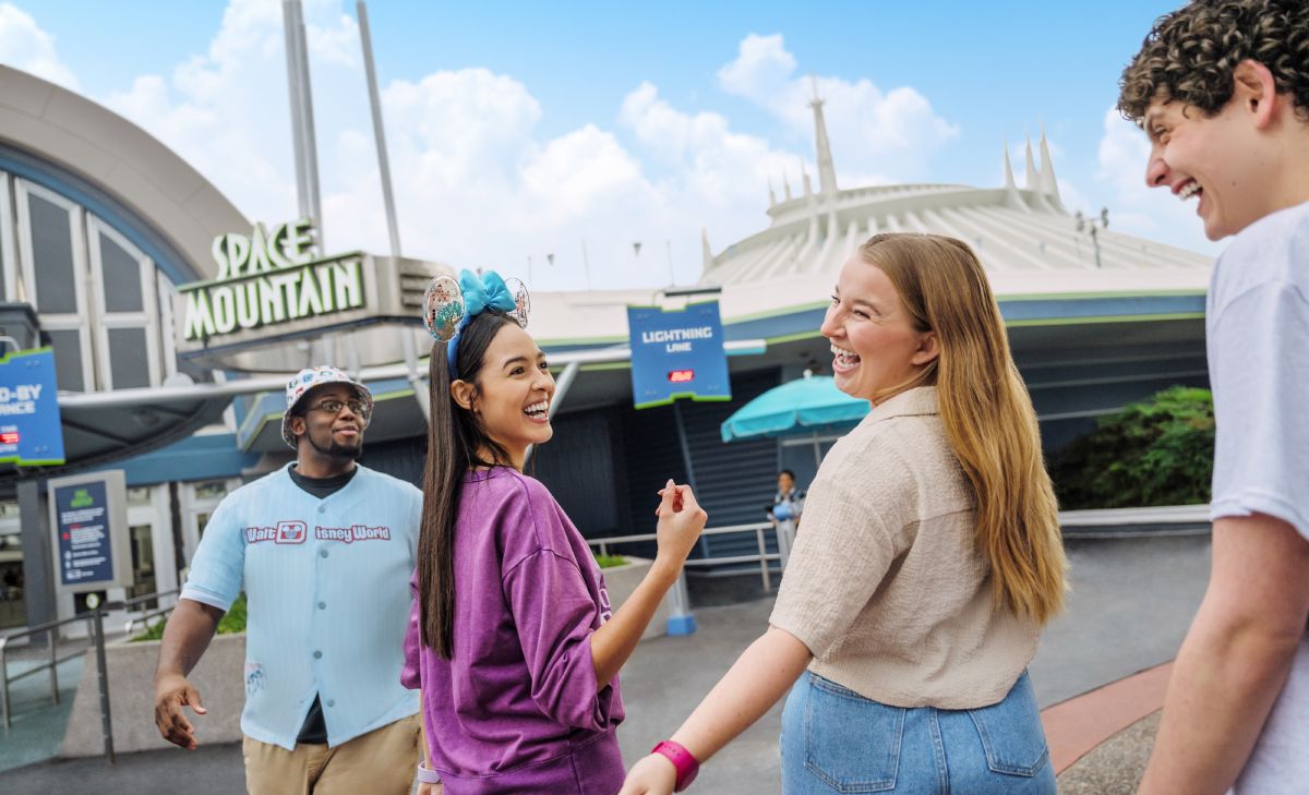 A group of friends laughing as they tap into the Lightning Lane entrance at Space Mountain in Magic Kingdom, showing how the shorter Lightning Lane queue works.