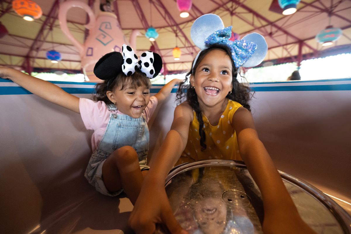 Two children laugh while spinning in a teacup on the Mad Tea Party ride at Magic Kingdom Park, Walt Disney World Resort.