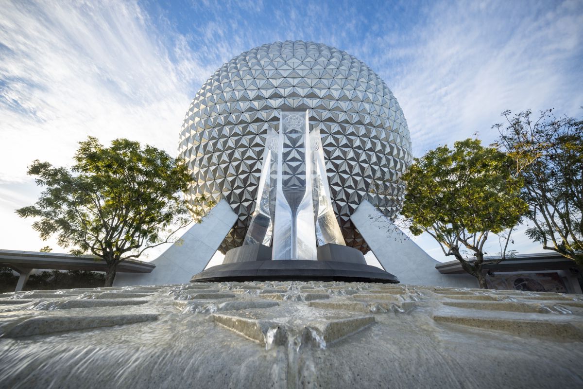 Spaceship Earth towers behind a fountain at the entrance to EPCOT, one of four theme parks included on a Walt Disney World ticket.