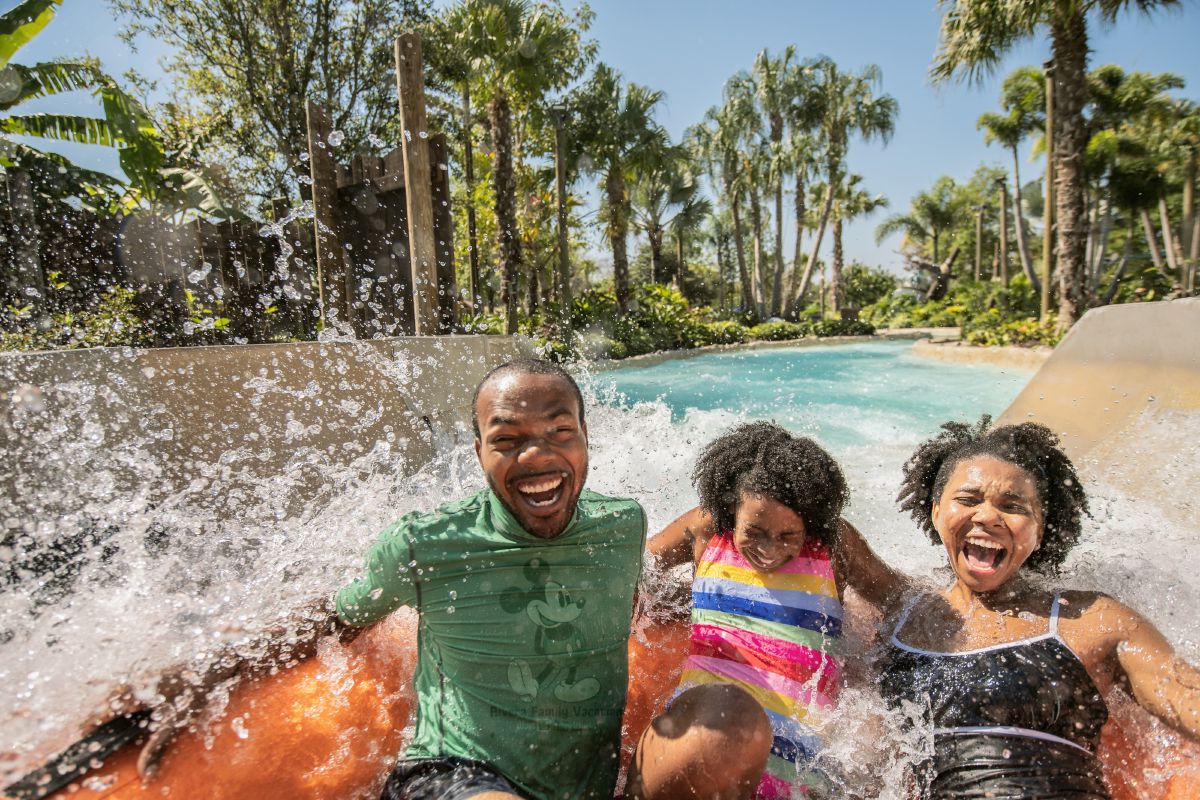 Father and two kids laughing together as they splash in the water at Disney's Typhoon Lagoon Water Park.