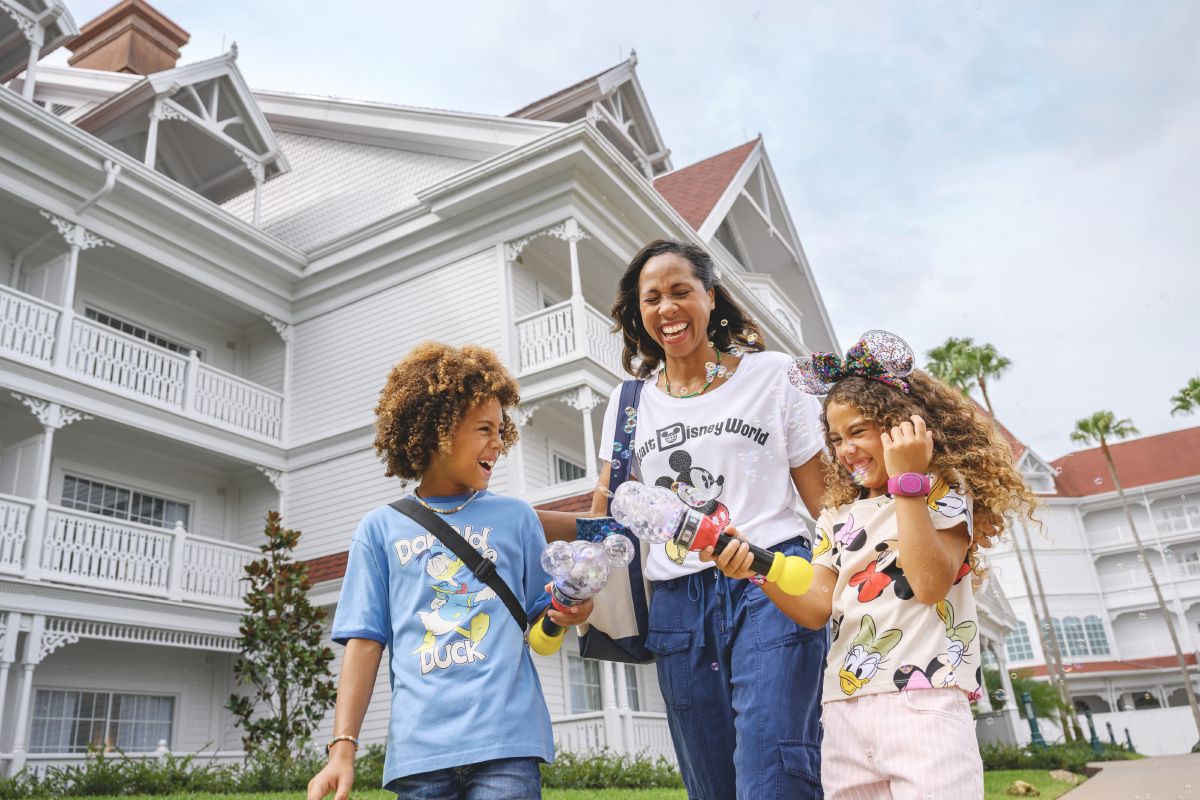 A mother and two children walking along a pathway outside Disney's Grand Floridian Resort & Spa, one of the Deluxe Disney Resort hotels at Walt Disney World.